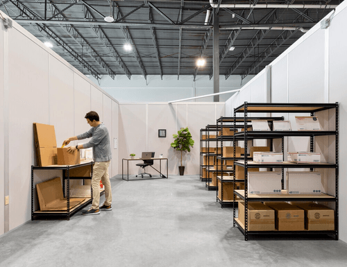 Person working inside a private flex warehouse unit with shelving, boxes, and workspace